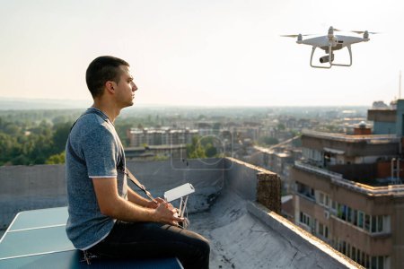 Téléchargez les photos : Jeune technicien homme volant drone UAV avec télécommande en ville en plein air - en image libre de droit