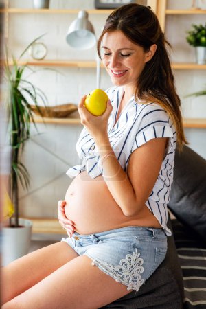 Téléchargez les photos : Grossesse, alimentation saine et concept de personnes Joyeux jeune femme enceinte mangeant des pommes. aliments sains. - en image libre de droit