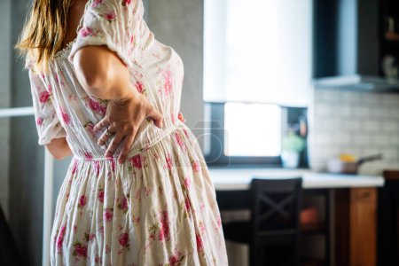 Téléchargez les photos : Jeune femme enceinte qui attend un bébé avec douleurs, nausées, maux de tête et maux de dos à la maison - en image libre de droit