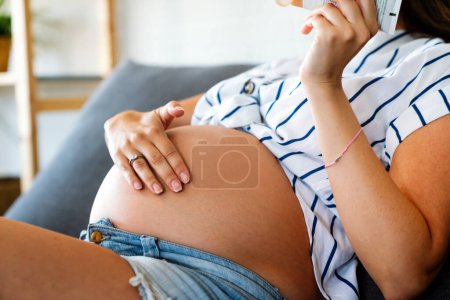 Photo for Care about perfect and smooth skin in pregnancy time. Pregnant woman using stretch mark cream at home - Royalty Free Image