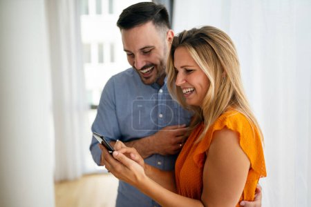 Photo for Portrait of happy couple having fun, using mobile phone together. People technology concept - Royalty Free Image