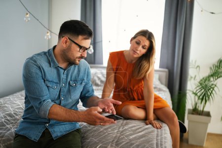 Téléchargez les photos : Jeune femme jalouse espionnant son petit ami et regardant son téléphone portable. Couple tricherie concept de jalousie - en image libre de droit