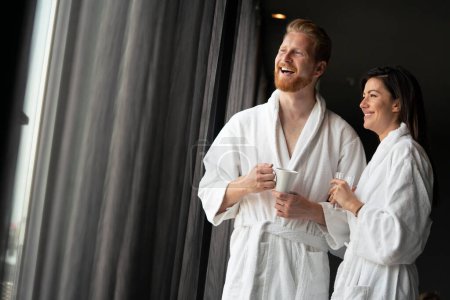 Téléchargez les photos : Couple en peignoirs profitant d'une lune de miel dans un hôtel moderne - en image libre de droit