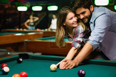 Photo for Portrait of young couple having fun playing billiard together at pub - Royalty Free Image