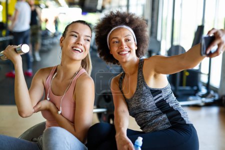 Photo for Beautiful young women working out in gym together to stay healthy. Sport, people, friend concept. - Royalty Free Image