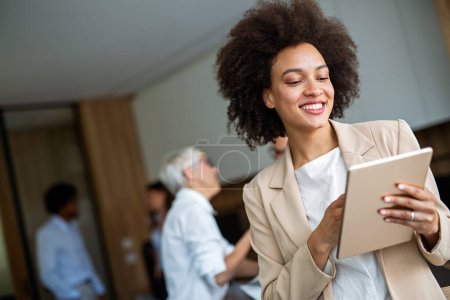 Happy black business woman manager holding tablet and working in modern office