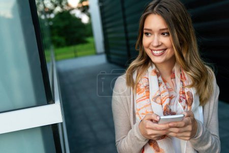 Foto de Mujer feliz sosteniendo el teléfono móvil, chat de mensajería en línea y la red social en el móvil. Concepto de tecnología. - Imagen libre de derechos