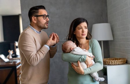 Foto de Joven padre infeliz con bebé y esposa que sufren de depresión postnatal en casa. - Imagen libre de derechos