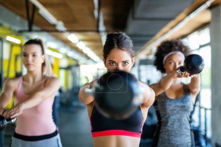 Photo for Multiethnic group of people training in a gym. Trainer and sportive fit persons exercising in a fitness class - Royalty Free Image