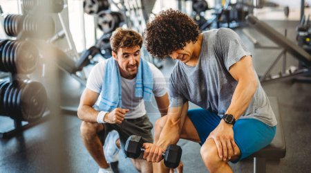Photo for Fitness, sport, exercising and diet concept. Happy fit man exercising together with his personal trainer, friend in gym. - Royalty Free Image