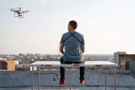 Foto de Joven técnico hombre que vuela dron UAV con control remoto en la ciudad al aire libre - Imagen libre de derechos