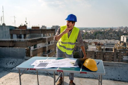 Téléchargez les photos : Jeune homme d'affaires de succès ingénieur de chantier travaillant avec les plans de l'architecte sur le chantier de construction. - en image libre de droit