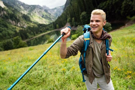 Téléchargez les photos : Homme heureux voyageant avec sac à dos randonnée en montagne - en image libre de droit