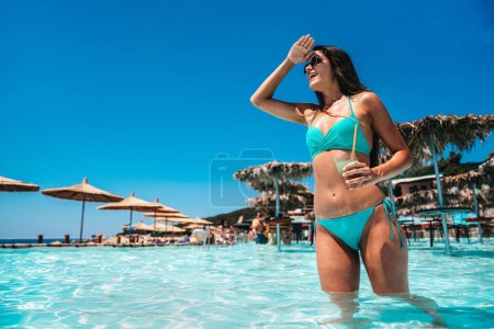 Foto de Mujer joven en traje de baño con cóctel en la playa disfrutando de las vacaciones de verano. Tropical paraíso escapada viaje turismo concepto. - Imagen libre de derechos
