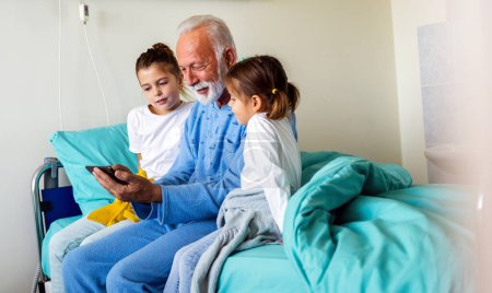 Photo for Happy senior man is recovering from the coronavirus is visited by his grandchildren - Royalty Free Image