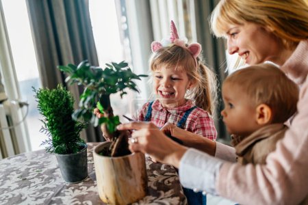 Téléchargez les photos : Des enfants mignons aident sa mère à prendre soin des plantes. Maman et ses enfants font du jardinage à la maison. Concept de passe-temps familial. - en image libre de droit