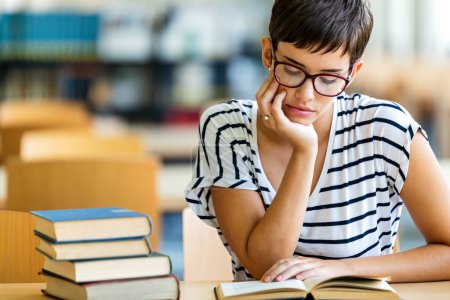 Photo for Exhausted young tired female studying and preparing for exam in college library. Education people concept - Royalty Free Image