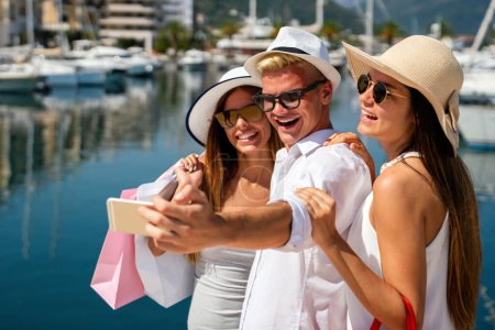 Téléchargez les photos : Groupe d'amis heureux multiraciaux prenant selfie et s'amusant sur une plage pendant les vacances d'été. Voyage gens shopping concept. - en image libre de droit