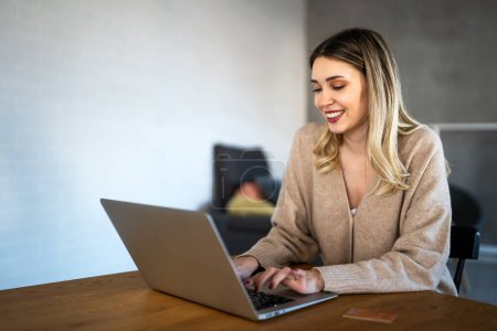 Foto de Mujer bonita sonriente usando el ordenador portátil para el trabajo freelance medios sociales o relajación. Concepto de tecnología. - Imagen libre de derechos