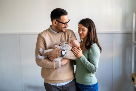Photo for Proud mother and father smiling at their newborn baby daughter, son at home. Happy family concept - Royalty Free Image