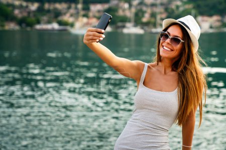 Photo for Beautiful woman having a good time at the beach on summer vacation, taking a selfie. People technology social media concept. - Royalty Free Image