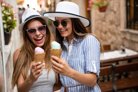 Photo for Happy young women friends enjoying ice cream together on summer vacation. People travel happiness concept. - Royalty Free Image