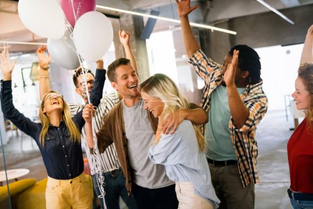 Téléchargez les photos : Joyeux jeune succès multiethnique équipe d'affaires célébrant un triomphe avec les bras vers le haut dans le bureau de démarrage. - en image libre de droit