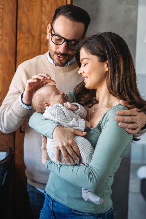 Photo for Peaceful young married couple enjoying being family, parents, holding new born baby in arms, standing close together. Parenthood, childbirth, relationship concept - Royalty Free Image