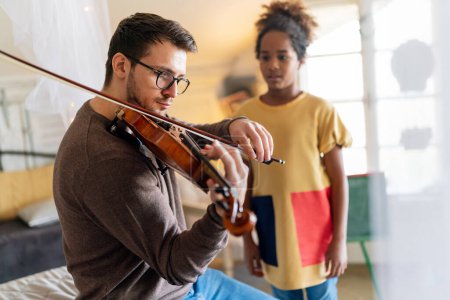 Photo for Music is so much fun. Young father teaching his little daughter to play violin and smiling. Parent child happiness concept. - Royalty Free Image