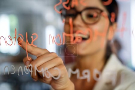 Téléchargez les photos : Femme écrivant sur verre pendant l'atelier dans l'espace de coworking, prenant des notes d'information pendant la stratégie de planification du flux de travail pour le projet de démarrage - en image libre de droit