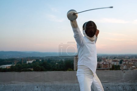 Foto de Woman in white fencing costume practicing outdoors. Expensive sport, professional coach, healthy lifestyle. - Imagen libre de derechos