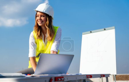 Foto de Joven mujer exitosa especialista en construcción arquitecto revisando planos en el sitio de construcción - Imagen libre de derechos