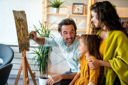 Foto de Concepto familiar feliz. Jóvenes padres sonrientes con niños pintando juntos en casa. Gente divertida felicidad. - Imagen libre de derechos