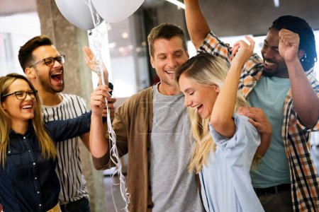 Téléchargez les photos : Happy multiracial jeune groupe de gens d'affaires s'amuser tout en célébrant sur la fête surprise dans le bureau. - en image libre de droit