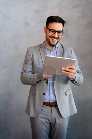 Téléchargez les photos : Portrait de jeune homme d'affaires travaillant en ligne sur tablette numérique. Concept technologique des hommes d'affaires - en image libre de droit