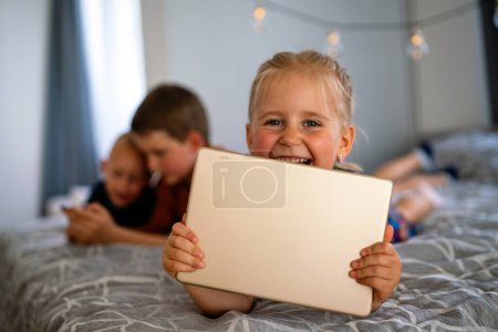 Foto de Retrato de niños felices usando dispositivos digitales y divirtiéndose juntos. Concepto de adicción a la tecnología infantil. - Imagen libre de derechos