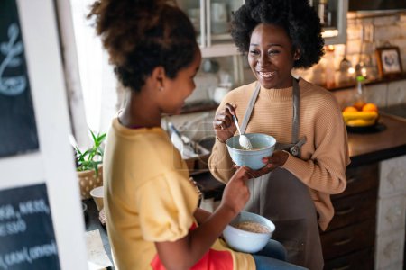 Foto de Feliz madre afroamericana y su hija desayunando y pasando tiempo de calidad juntos en la cocina - Imagen libre de derechos