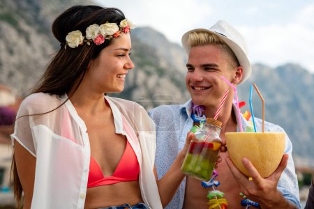 Photo for Couple drinking alcohol cocktails at beach at sunset. Happy multiethnic young couple in love are on a date, enjoying cocktails on the beach - Royalty Free Image
