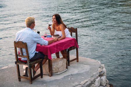 Foto de Una pareja está teniendo una cena privada en una playa tropical durante el atardecer. Concepto de viaje de luna de miel - Imagen libre de derechos