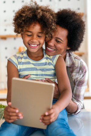 Téléchargez les photos : Portrait de femme noire heureuse et sa fille préadolescente mignonne s'amusant ensemble à la maison, Happy afro-américaine lien de famille, embrasser et sourire - en image libre de droit