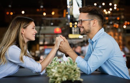 Photo for Handsome young man and attractive young woman are spending time together. Romantic couple in cafe is drinking coffee and enjoying being together. - Royalty Free Image