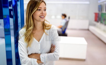 Foto de Mujer de negocios exitosa de pie en una oficina creativa mientras sonríe. Concepto de mujer exitosa. - Imagen libre de derechos