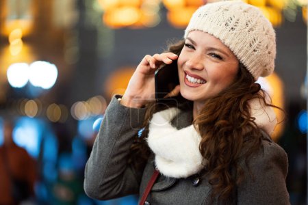 Foto de Retrato de mujer feliz sonriente usando teléfono móvil en la ciudad en invierno. Concepto de comunicación - Imagen libre de derechos