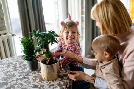 Foto de Lindos niños pequeños con madre cuidando plantas en el interior. Familia diversión hogar jardinería concepto. - Imagen libre de derechos