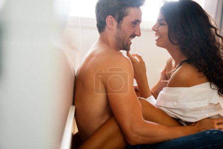 Photo for Sensual young couple together in bed. Happy couple in love in bedroom enjoying sensual foreplay. - Royalty Free Image