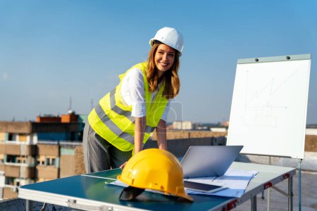 Photo for Young successful woman construction specialist architect reviewing blueprints at construction site - Royalty Free Image