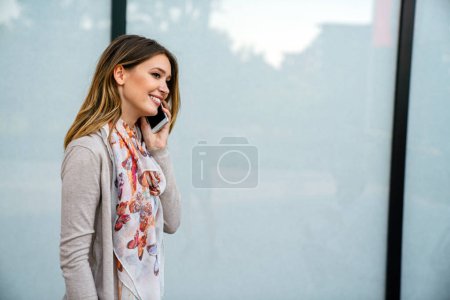Téléchargez les photos : Portrait en plein air de belle jeune entreprise, fille étudiante riant et utilisant un téléphone portable - en image libre de droit