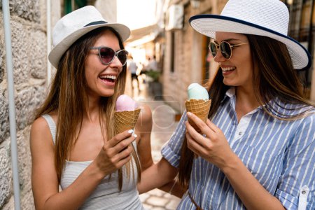 Photo for Happy young women friends enjoying ice cream together on summer vacation. People travel happiness concept. - Royalty Free Image