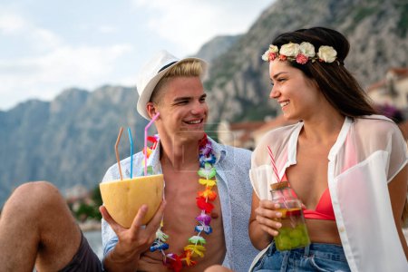 Photo for Multicultural trendy couple having fun drinking cocktails at beach party. Summer joy and life style concept with young people at festival - Royalty Free Image