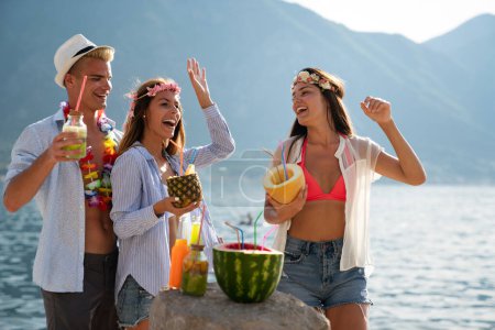 Foto de Grupo de jóvenes amigos en la playa tomando cócteles divirtiéndose en las vacaciones de verano. Concepto de viaje - Imagen libre de derechos